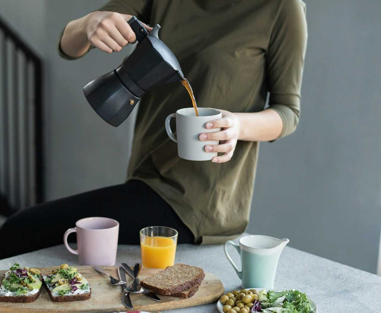 woman-in-green-top-pouring-coffee-in-a-white-mug-3754296